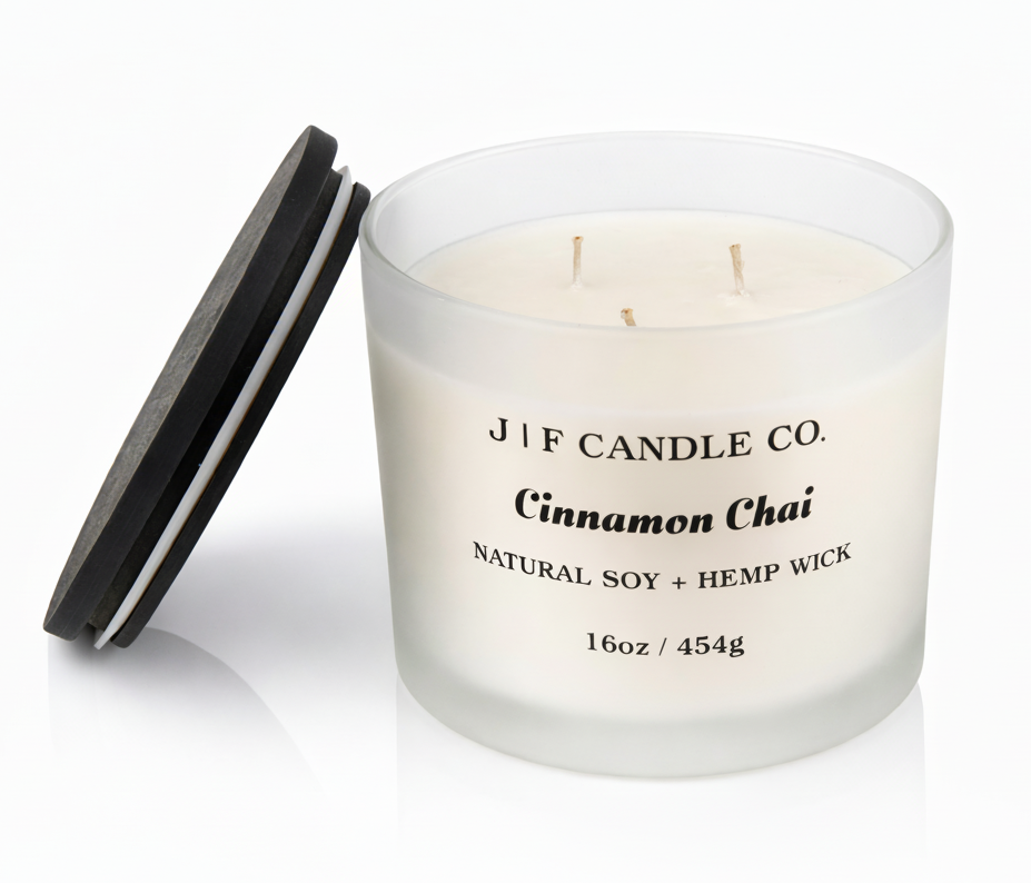 J | F Candle Co. Cinnamon Chai 16oz triple wick soy candle in a frosted glass jar with wooden lid placed beside it on a clean white background with a soft reflection.