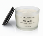 J | F Candle Co. Citronella 16oz triple wick soy candle in frosted glass jar with wooden lid placed beside it on a clean white background with soft reflection
