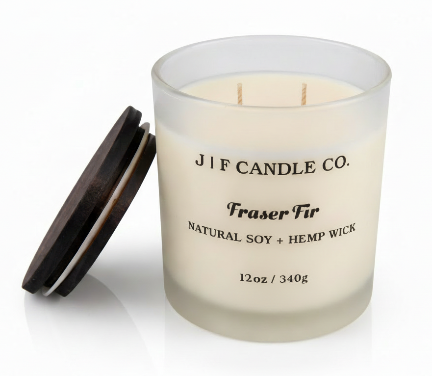 J | F Candle Co Fraser Fir 12oz soy candle in frosted glass jar with wooden lid beside candle on white background