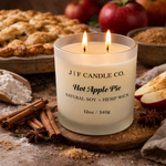 Luxury hot apple pie soy candle by J | F Candle Co with double lit wicks in frosted glass jar, styled with cinnamon sticks, apples, brown sugar, and fresh baked pie on a rustic wood surface