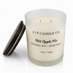 J | F Candle Co. Hot Apple Pie 12 oz soy candle in a frosted glass jar with the dark wood lid placed beside it on a clean white background with a soft reflection.