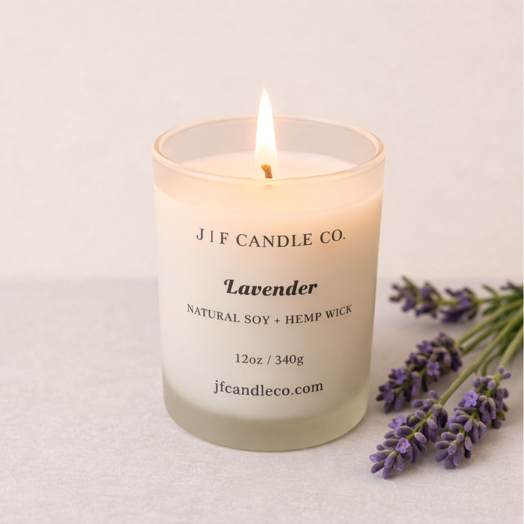 Lavender luxury soy candle by J | F Candle Co. in frosted glass jar with hemp wick, styled with fresh lavender sprigs in soft natural light.