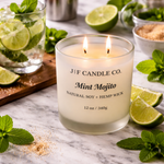 Luxury mint mojito soy candle by J | F Candle Co with double lit wicks in frosted glass jar, styled with fresh mint leaves, lime wedges, sugar crystals, and mojito cocktail on a marble surface