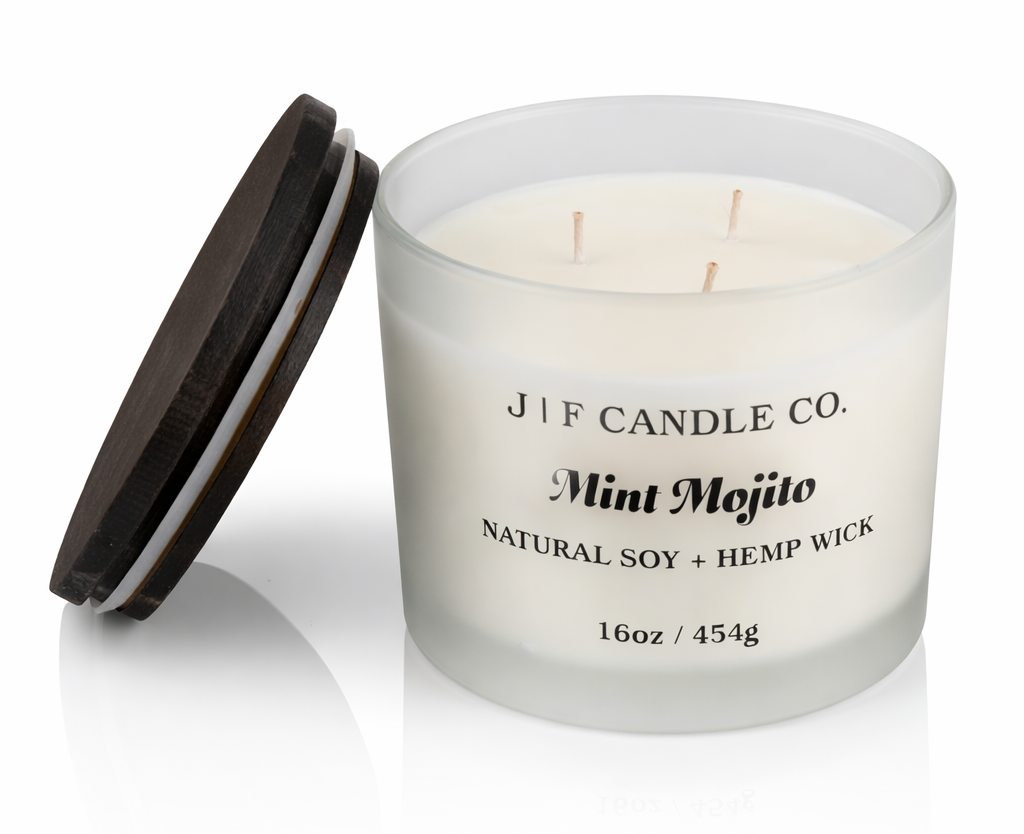 J | F Candle Co Mint Mojito luxury soy candle, 16 oz three-wick in frosted glass jar with wooden lid beside candle, clean white background with soft reflection