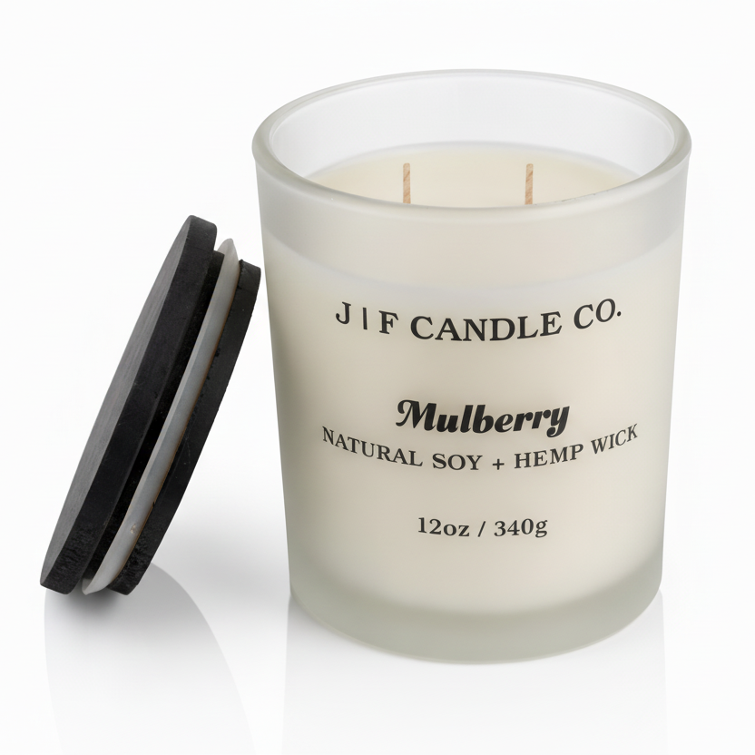 J | F Candle Co Mulberry luxury soy candle in 12oz frosted glass jar with wooden lid beside candle and soft reflection on clean white background