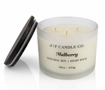 J | F Candle Co Mulberry luxury soy candle in 16oz frosted glass jar with three wicks and wooden lid beside candle on clean white background with soft reflection