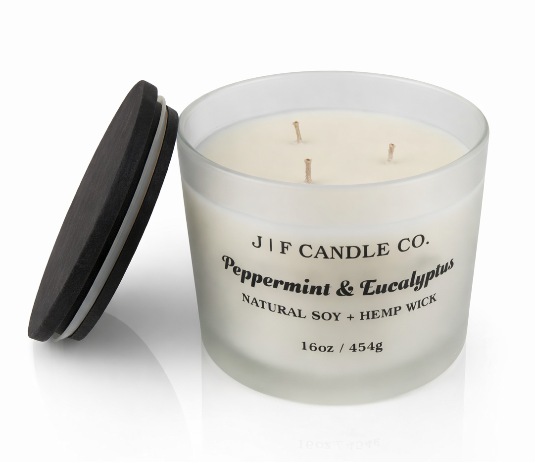 J | F Candle Co Peppermint & Eucalyptus 16oz three wick soy candle in frosted glass jar with wooden lid beside candle, clean white background with soft reflection, luxury spa-inspired scent
