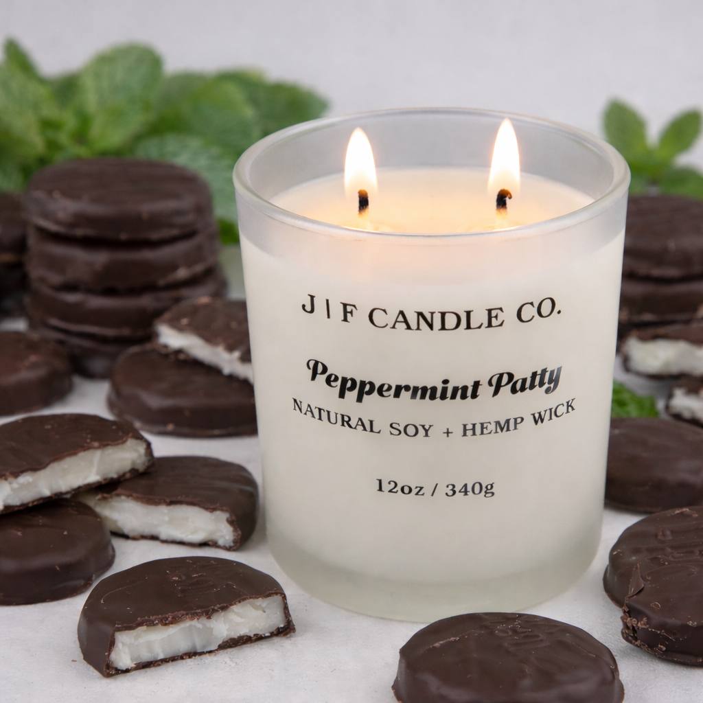 J | F Candle Co Peppermint Patty soy candle 12oz with double wick lit, styled with chocolate peppermint patties and fresh mint in a luxury lifestyle setting without website text on label