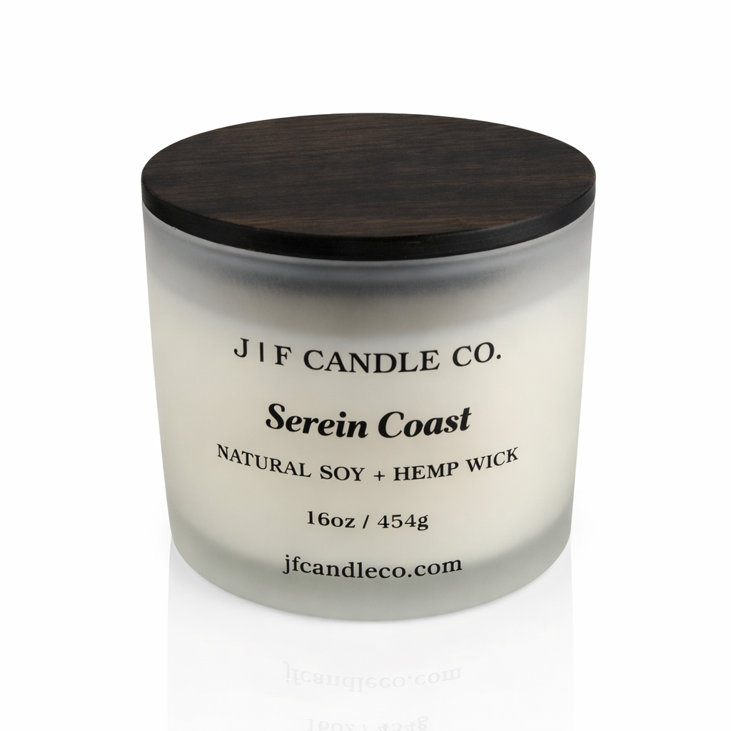 16 oz Serein Coast soy candle in a frosted glass jar with wooden lid on a white background with soft reflection, by J | F Candle Co.