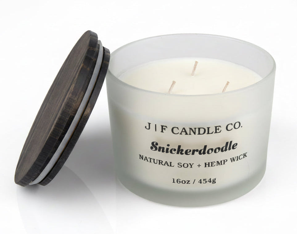 Luxury Snickerdoodle soy candle by J | F Candle Co. in frosted glass jar with wood lid beside candle, 16 oz clean-burning candle with soft reflection