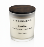 J F Candle Co Vanilla soy candle in frosted glass jar with wooden lid and soft reflection, clean white background luxury candle product photo