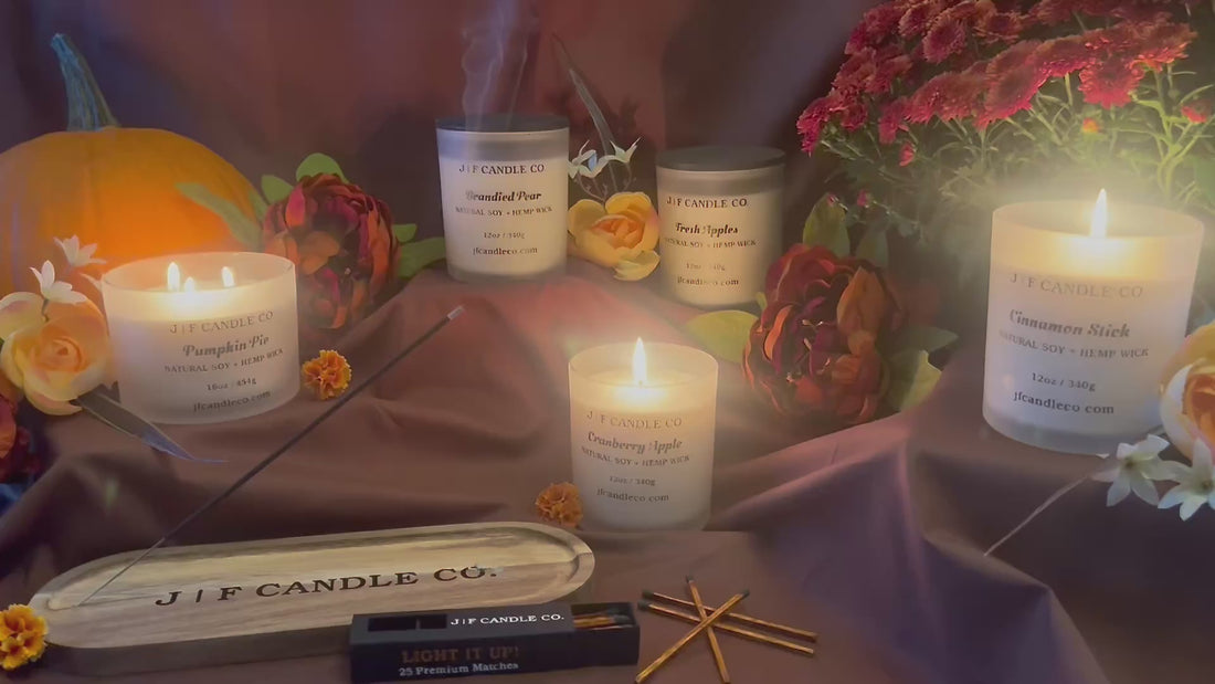 Short video featuring J | F Candle Co. fall candles with a lit Cranberry Apple incense stick resting in a tray. A pumpkin sits in the background on one side and a fall mum on the other, creating a warm seasonal atmosphere.